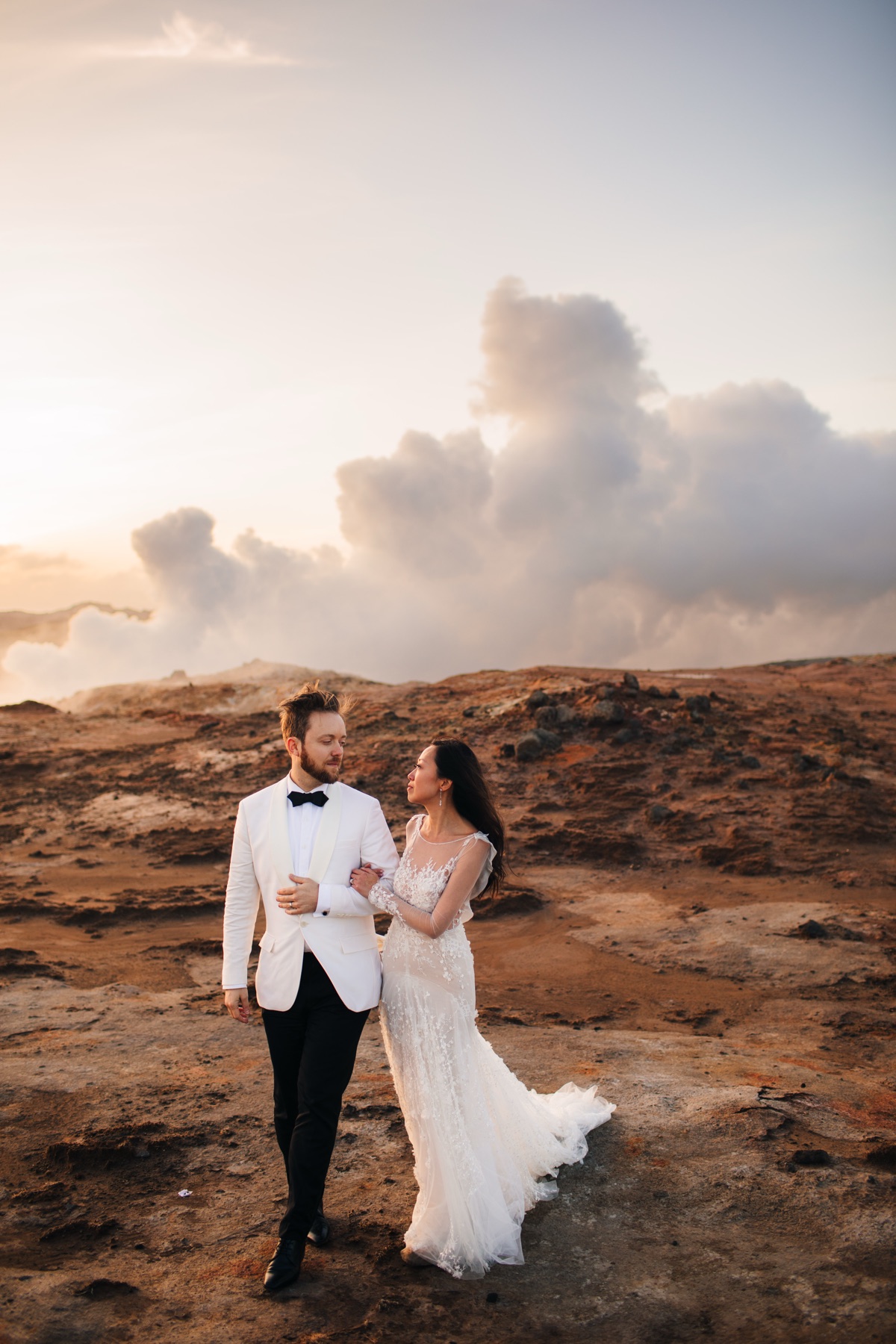 Iceland destination wedding — couple walking through volcanic landscape with geothermal steam